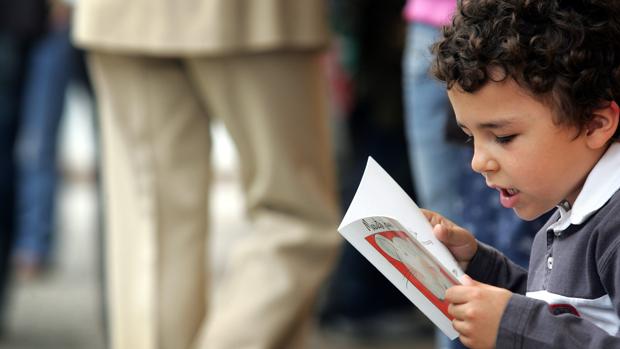 Un niño lee un libro infantil