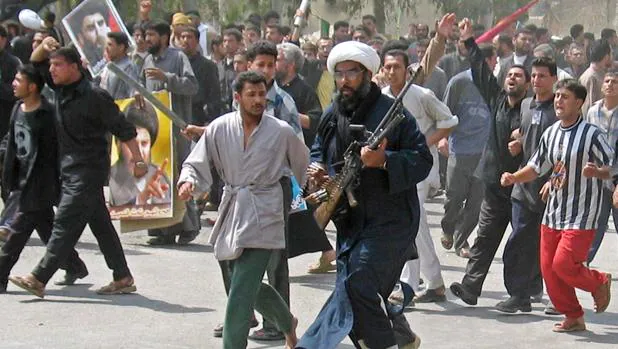 Foto de archivo de una multitud de manifestantes, entre ellos miembros del Ejército de Mehdi, una milicia iraquí prohibida que apoya al clérigo radical anti-estadounidense Moqtada al Sáder, marcha sobre una guarnición española en Nayaf en 2004