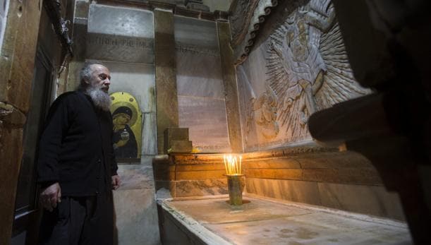 Un clero griego ortodoxo, fotografiado delante de la tumba de Jesucristo, en la Iglesia de la Santa Sepultura