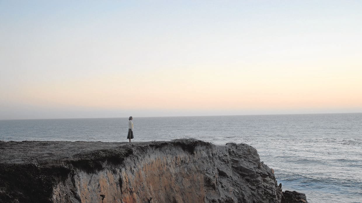 Una joven contempla el océano en un acantilado en California