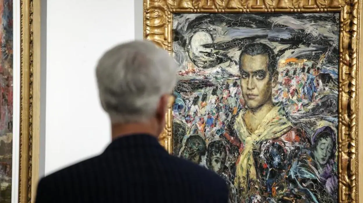 Un hombre observa el retrato de Federico García Lorca pintado por Enrique Ochoa