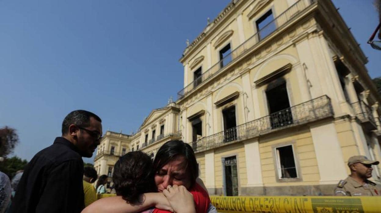 Dos funcionarias lloran ante la fachada del Museo Nacional de Río de Janeiro