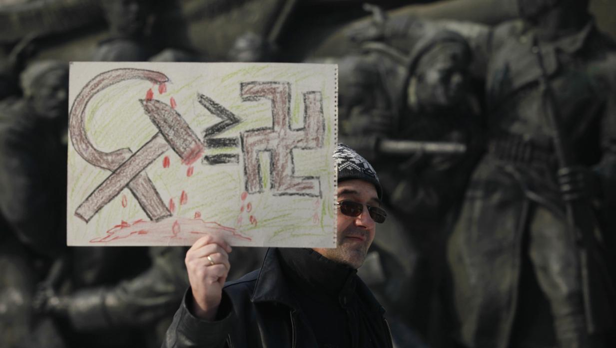 Un búlgaro sostiene una pancarta frente al monumento al ejército ruso durante una protesta a favor de su demolición