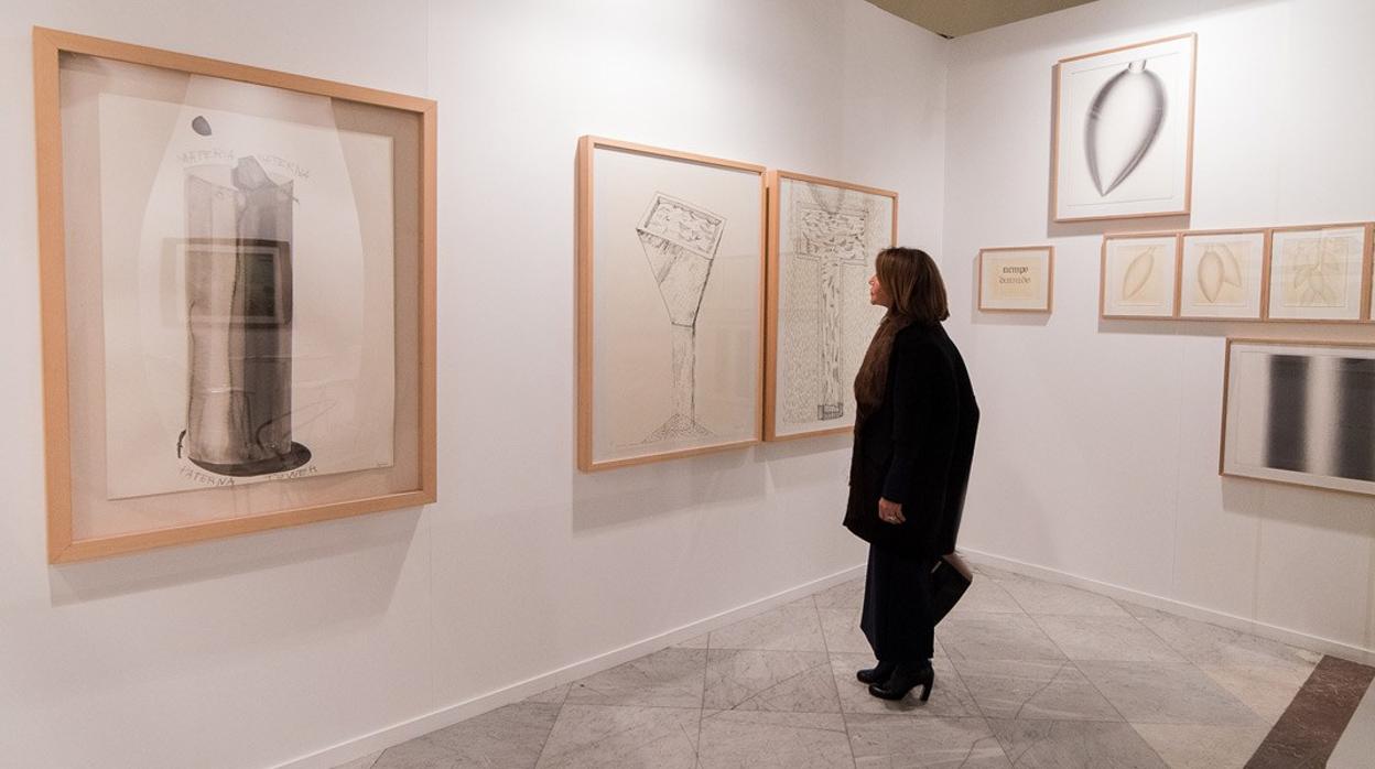 Una galerista muestra unos dibujos a unos visitantes de la feria Drawing Room