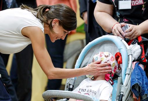 Doña Letizia hace un gesto cariñoso a una niña que visitaba la feria acompañada de sus padres