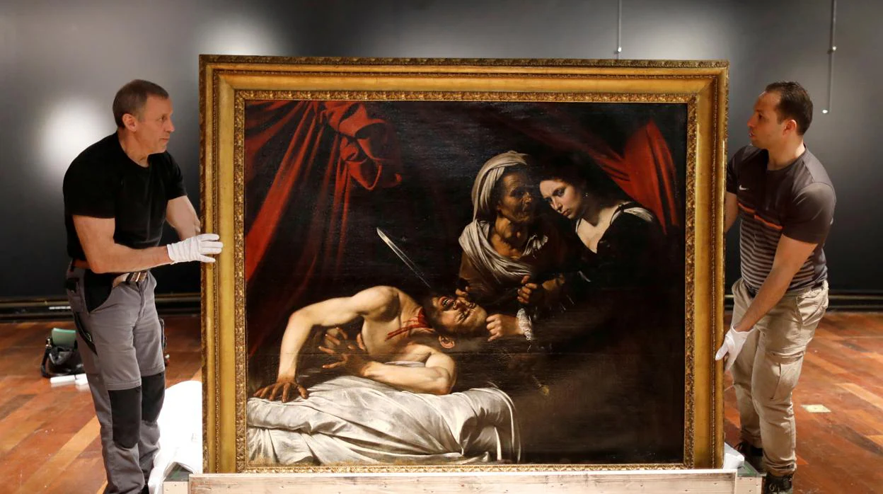 Dos operarios colocan la obra obra «Judith y Holofornes», atribuida a Caravaggio