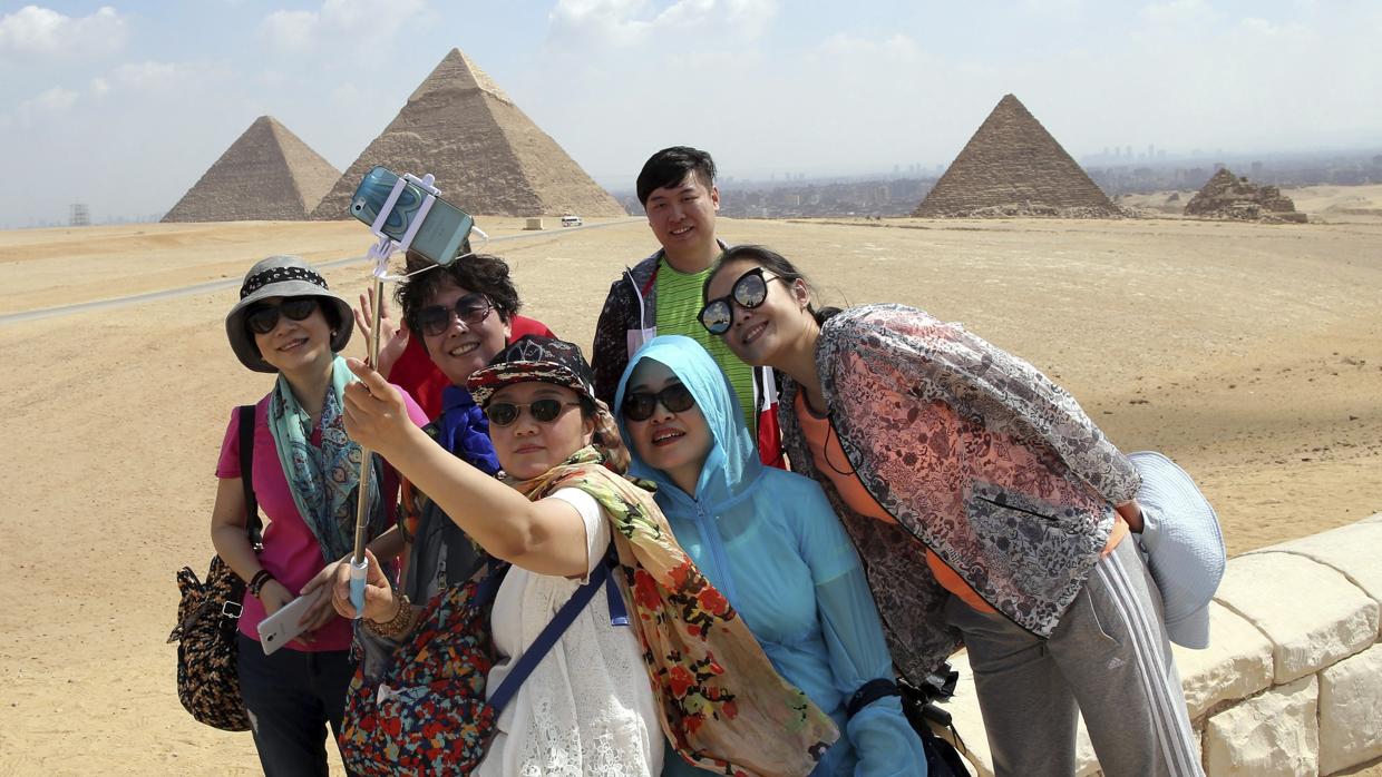 Un grupo de turistas se hace un selfie frente a las pirámides de Guiza, en Egipto