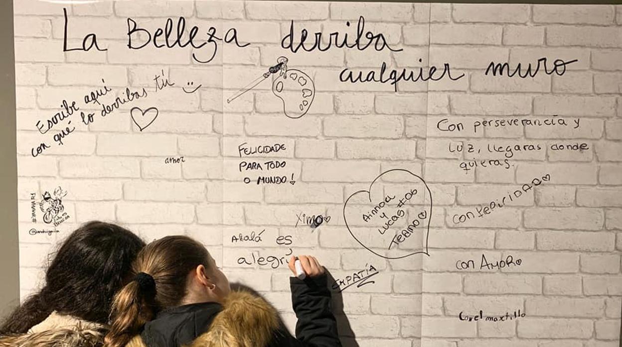 Dos chicas escribiendo en un muro de papel las cosas buenas de las Tres Mil Viviendas