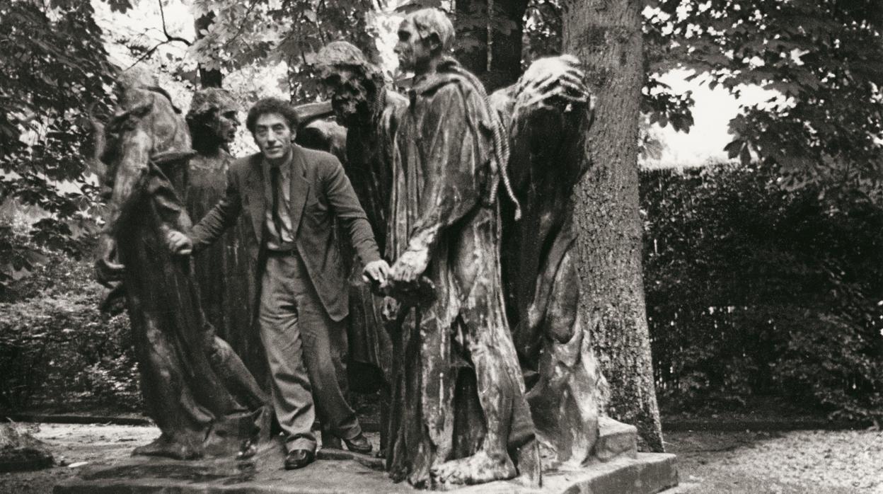 Alberto Giacometti, en el parque de Eugène Rudier en Vésinet, posando junto a «Los burgueses de Calais», de Rodin, en 1950