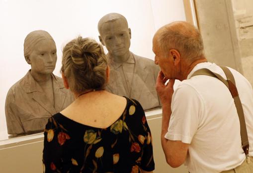 Antonio López y su esposa, María Moreno, en el Museo Thyssen junto con un retrato escultórico del matrimonio