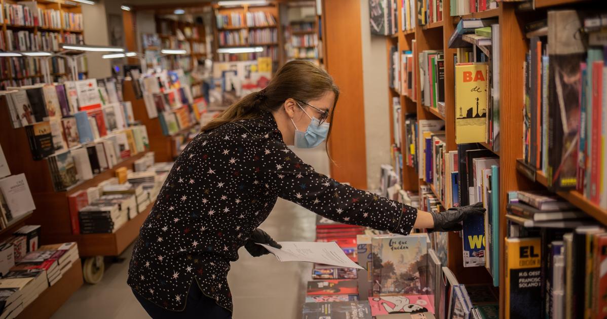 Una trabajadora de la librería Laie Pau Claris de Barcelona coloca libros y material en las estanterías del local, que permanece cerrado al público por la crisis del coronavirus, pero que el 22 de abril ha abierto para los trabajadores para prestar servicios online a los clientes que deseen obtener libros con motivo de Sant Jordi