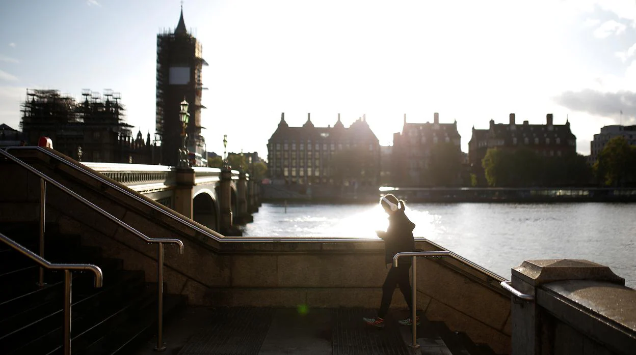 Una mujer pasea por el Westminster Bridge en una metrópoli vacía con el Parlamento y el Big Ben en plena restauración al fondo