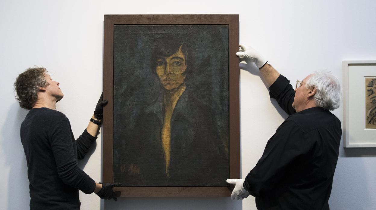 Operarios sostienen "Portrait Maschka Mueller", de Otto Müller, una de las obras de la colección Gurlitt