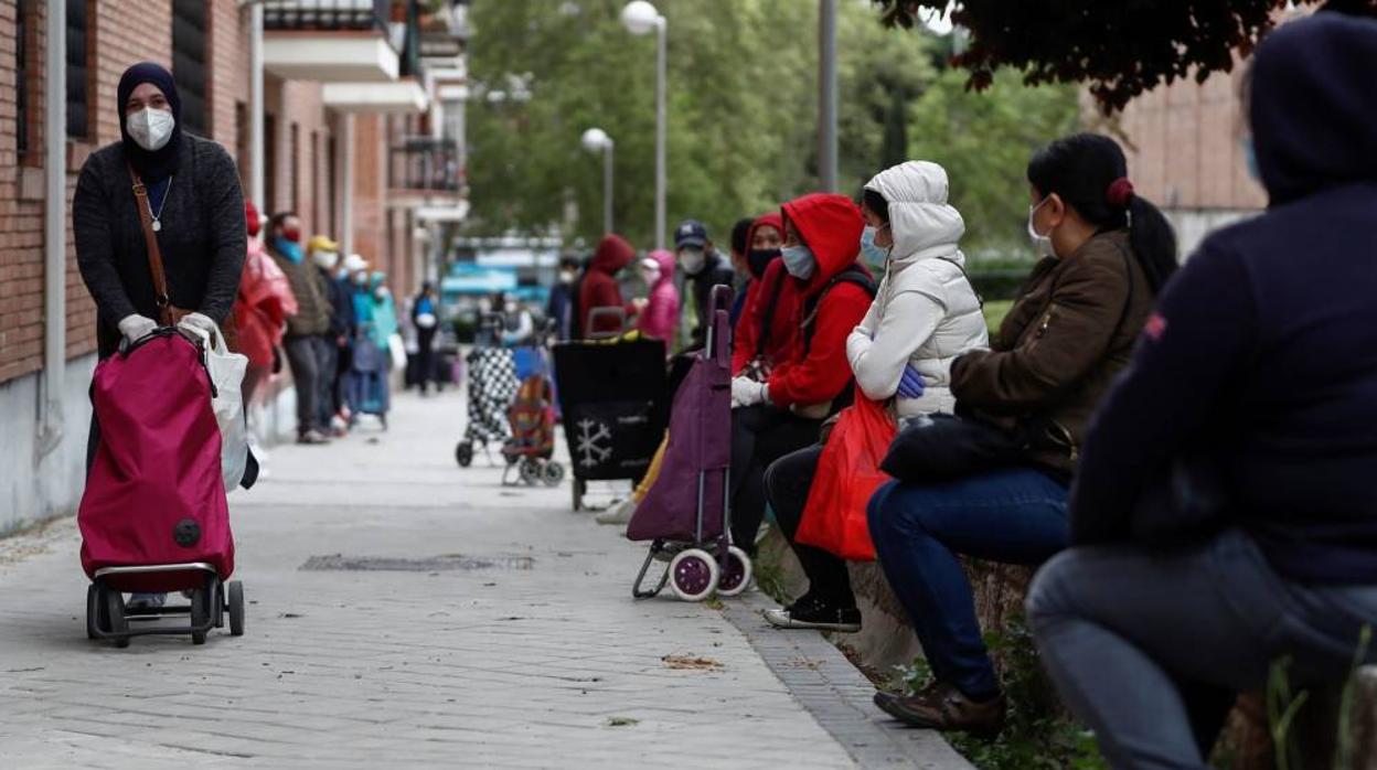 Personas hacen cola ante el Banco del Bebé de la Fundación Madrina, en la parroquia Santa María Micaela de Madrid, que diariamente reparte alimentos