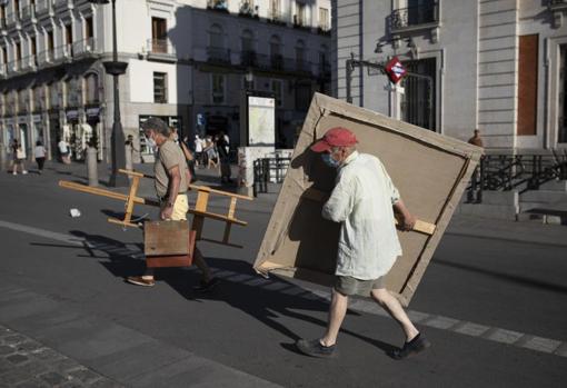 Antonio López traslada uno de los cuadros de la sede de la Comunidad al centro de la Puerta del Sol. Le ayuda a trasladar el caballete y los bártulos su amigo y también pintor Isidro Brunete