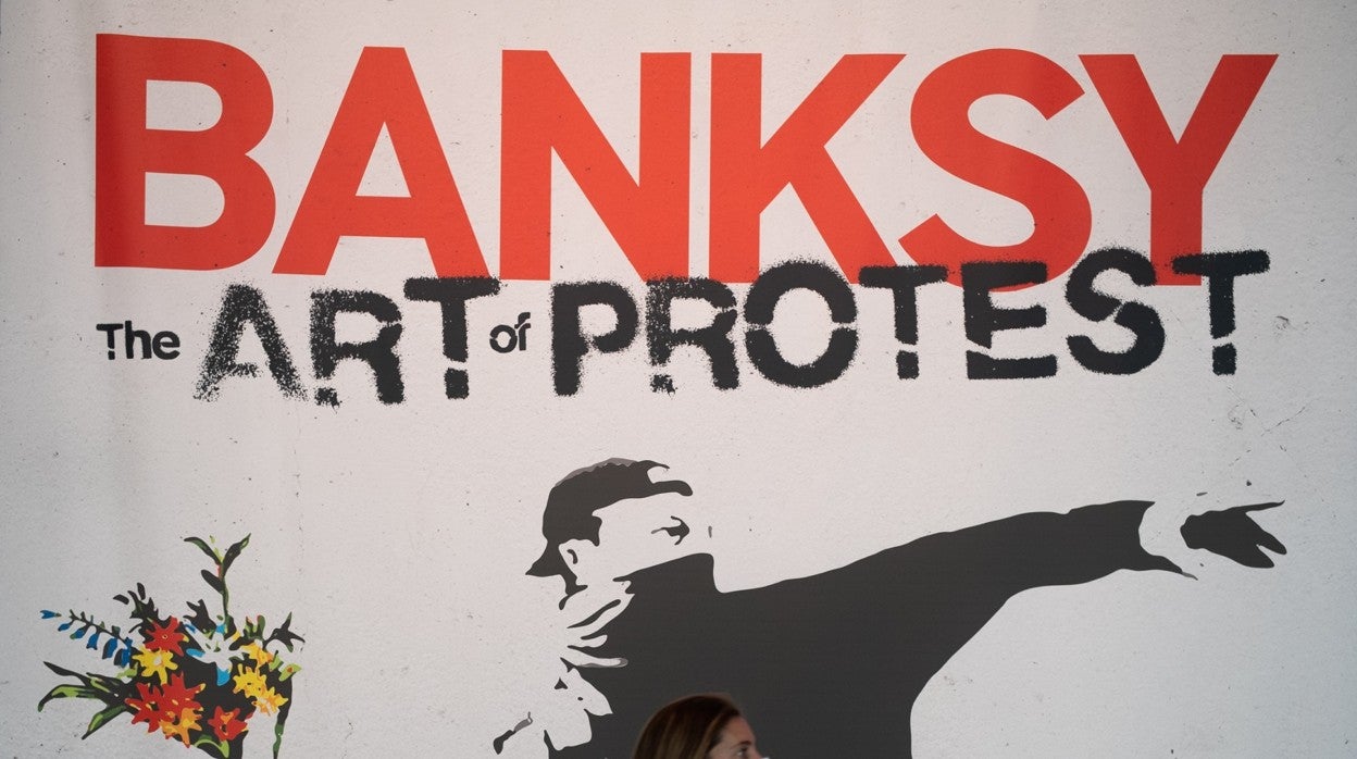 Una mujer pasa por delante de una reproducción de una obra de Banksy