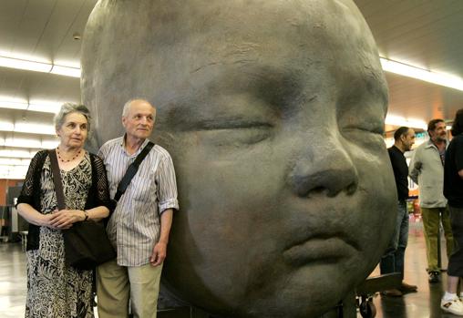 Antonio López, con su esposa, Mari, ante una de las dos cabezas de su nieta instaladas en la estación de Atocha. Después cambiaron su ubicación: salieron al exterior