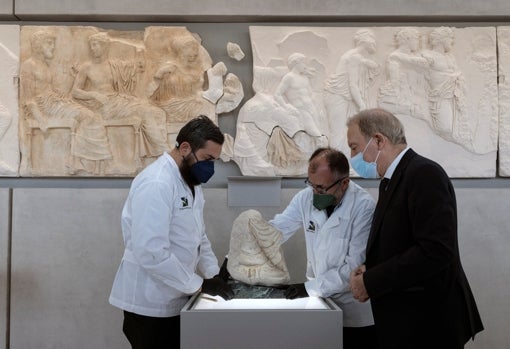 Dos conservadores sostienen en enero el fragmento del Partenón cedido por el Museo Arqueológico Regional Antonino Salinas de Palermo, mientras el director del Museo de la Acrópolis, Nikolaos Stampolidis, observa, en la Galería del Partenón del Museo de la Acrópolis.