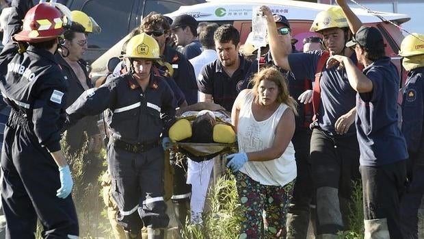 Los bomberos evacúan a uno de los heridos tras el accidente en el prólogo del Dakar