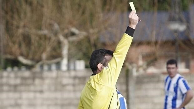 Un árbitro muestra una tarjeta amarilla durante un partido