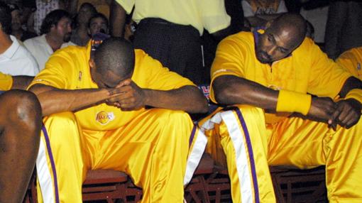 Malone (derecha) sentado junto a Kobe Bryant en un partido de exhibición de los Lakers en octubre de 2003