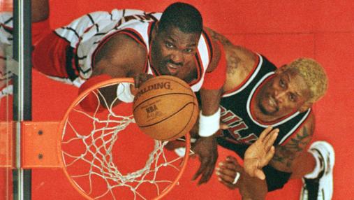 Rodman (derecha) lucha por el rebote con Hakeem Olajuwon en un partido en Abril de 1998