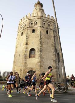 Participantes de la maratón en su paso por la Torre del Oro