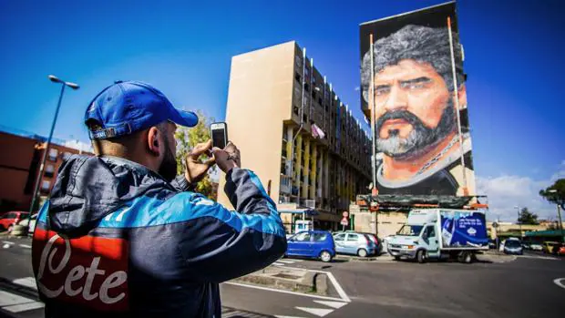 Un aficionado fotografía un muro con el rostro de Maradona