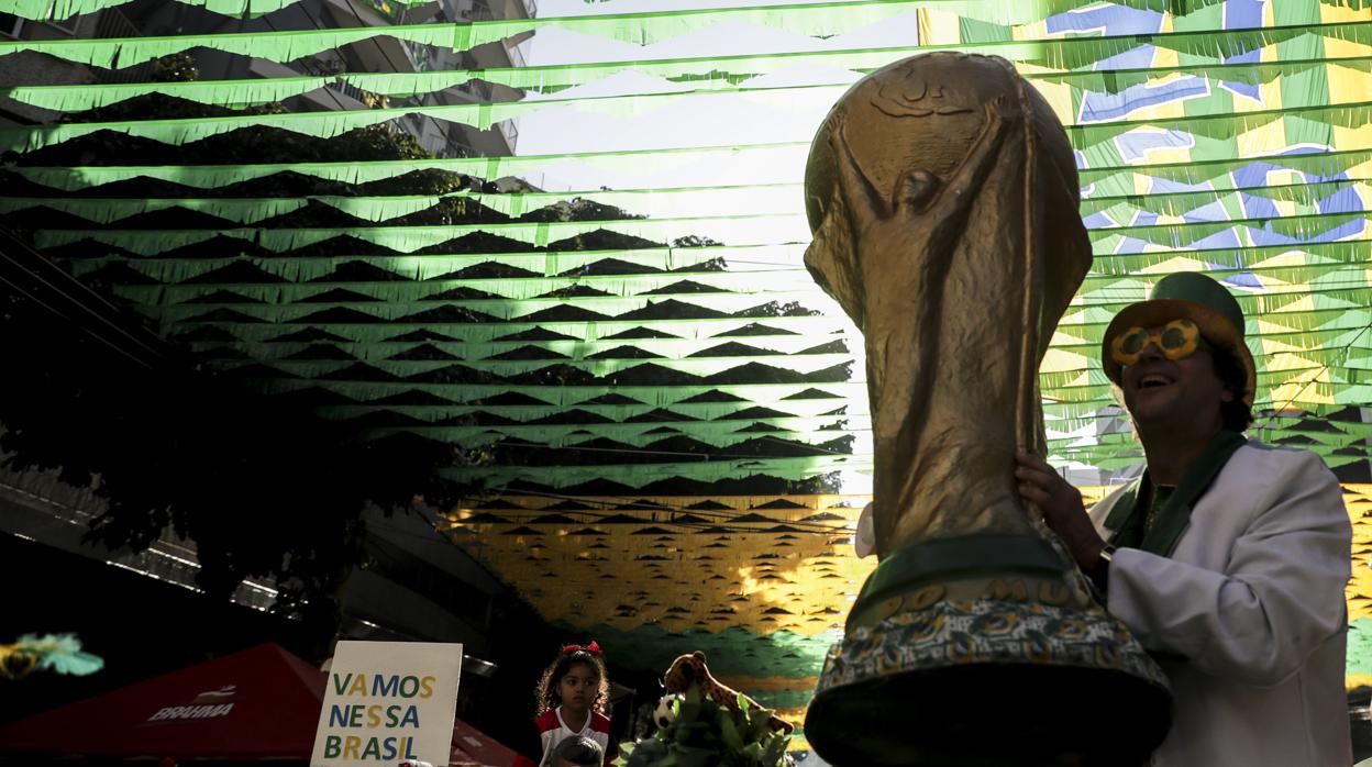 Aficionado brasileño sosteniendo una réplica de la Copa del Mundo