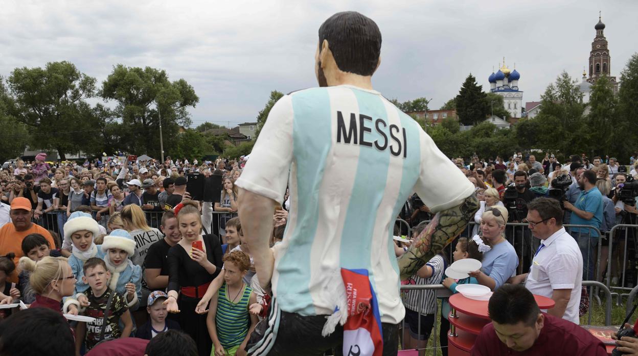 Varios aficionados, frente a una estatua de Messi