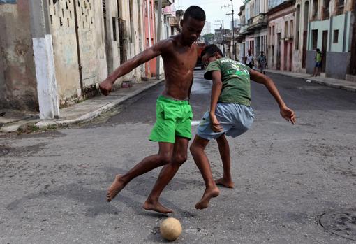 Dos cubanos juegan al fútbol en la calle