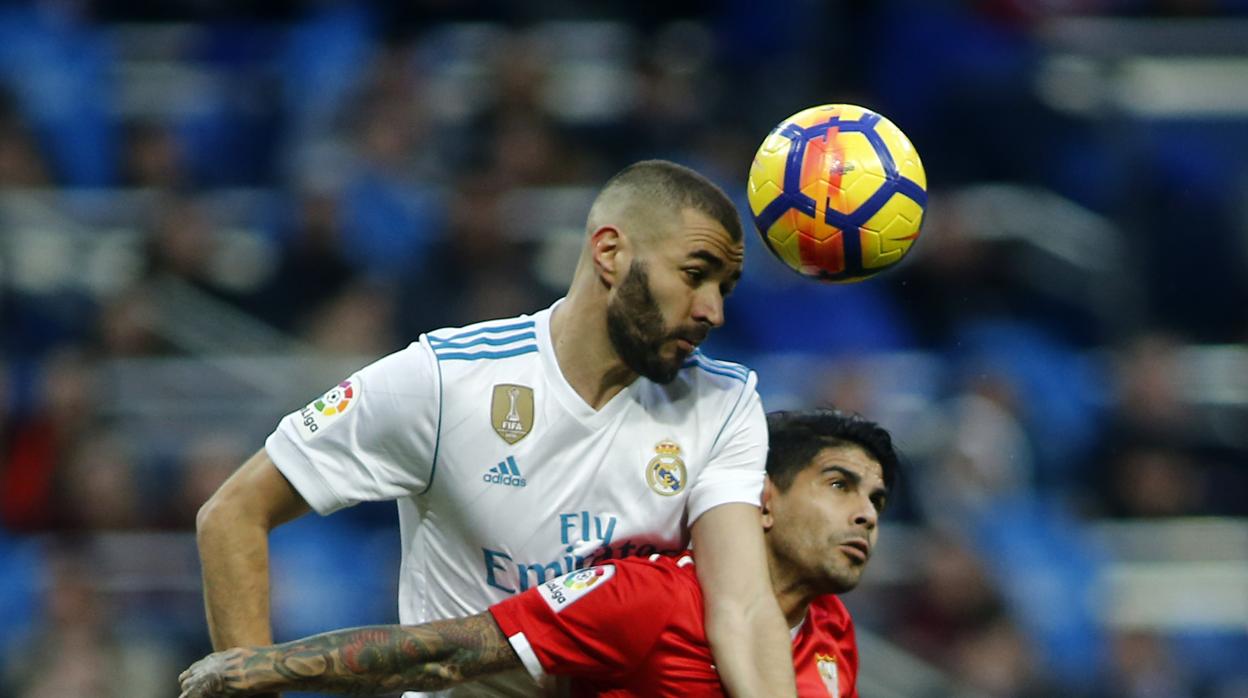 Benzema durante un Real Madrid - Sevilla, disputándole un balón a Banega