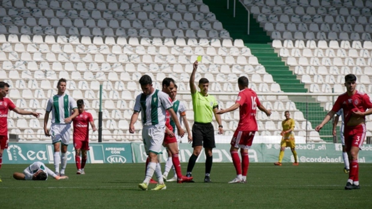 El árbitro amonesta ayer a Álex del Río, del Utrera, en el duelo frente al Córdoba B