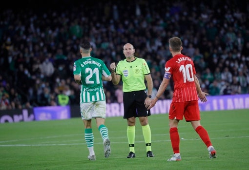 Mateu Lahoz habla con Guido Rodríguez ante Rakitic durante el derbi Betis - Sevilla