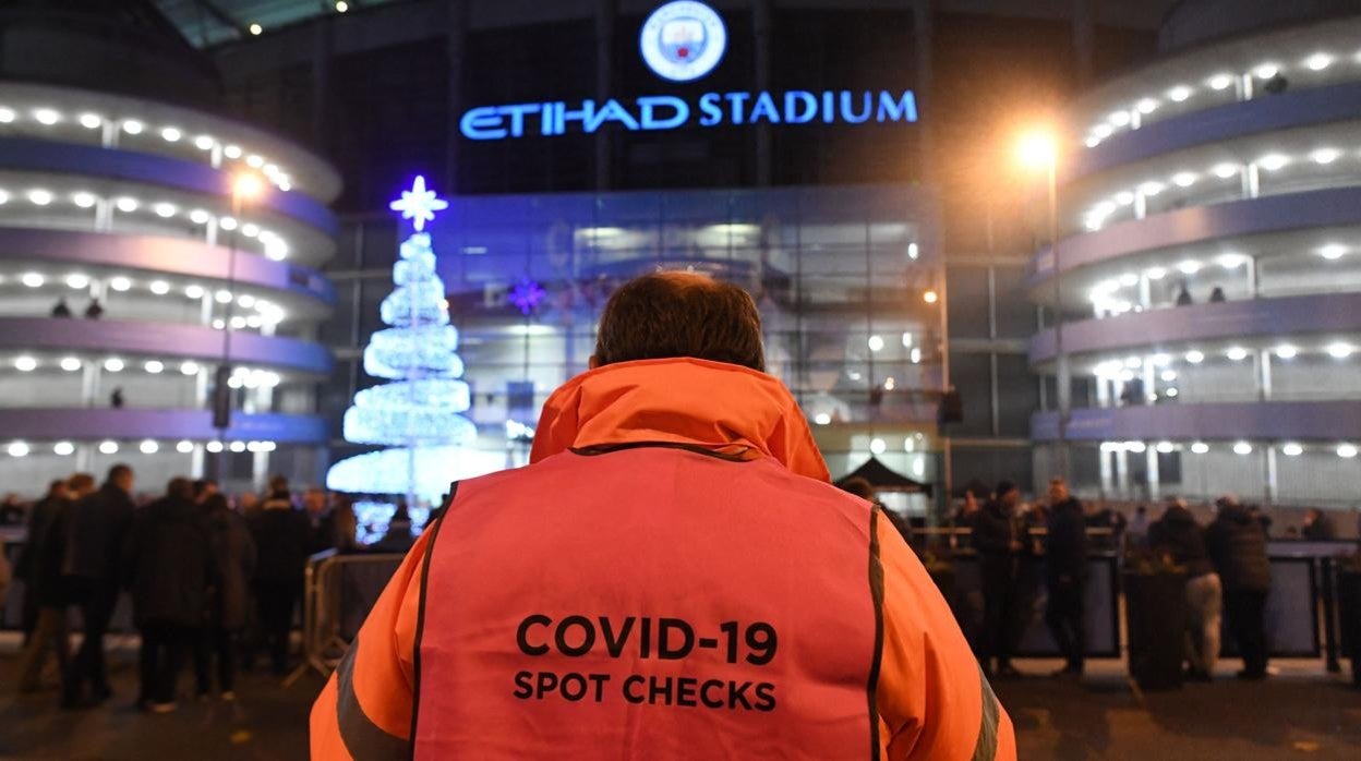 Un trabajador de la Premier hace controles de temperatura a la entrada del estadio del City