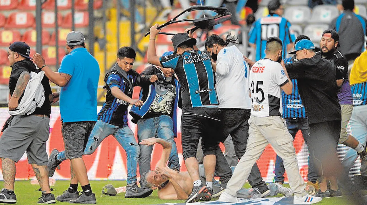 Hinchas de Querétaro golpeando a un aficionado de Atlas