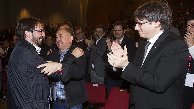 El nuevo secretario general, Camil Ros (izq), se abraza a su predecesor, José María Álvarez, en presencia del presidente de la Generalitat, Carls Puigdemont