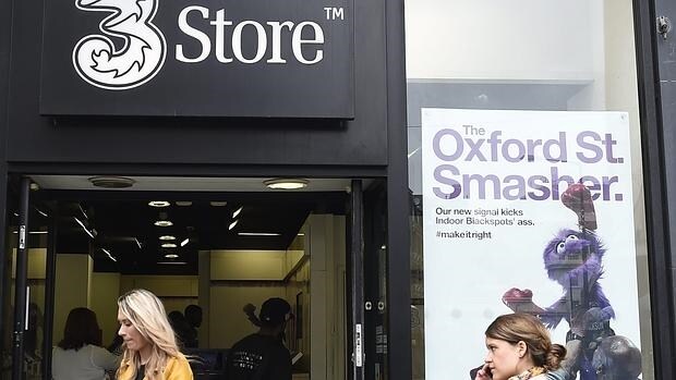 Dos mujeres pasan por delante de una tienda del operador móvil de Hutchison, Three, en Londres, Reino Unido, hoy, 11 de mayo de 2016