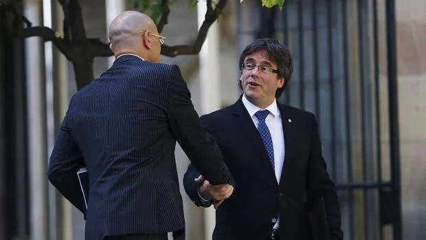 El Presidente de la Generalitat de Cataluña, Carles Puigdemont, se saluda con el Consejero de Exteriores Raül Romeva
