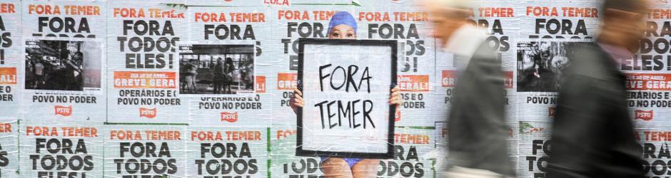 Una persona pasa frente a un muro lleno de carteles en contra del presidente de Brasil, Michel Temer