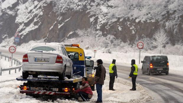 Una grúa asiste a un vehículo en una carretera nevada