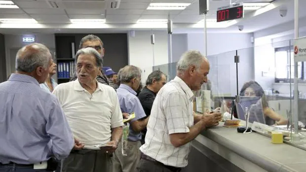 Jubilados hacen transacciones en una sucursal del banco Piraeus en Creta, Grecia