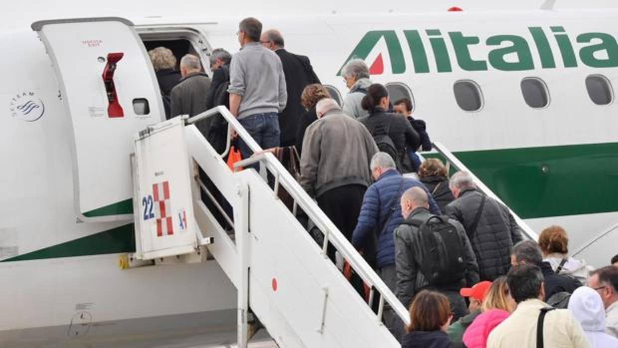Un grupo de pasajeros subiendo a un avión de Alitalia