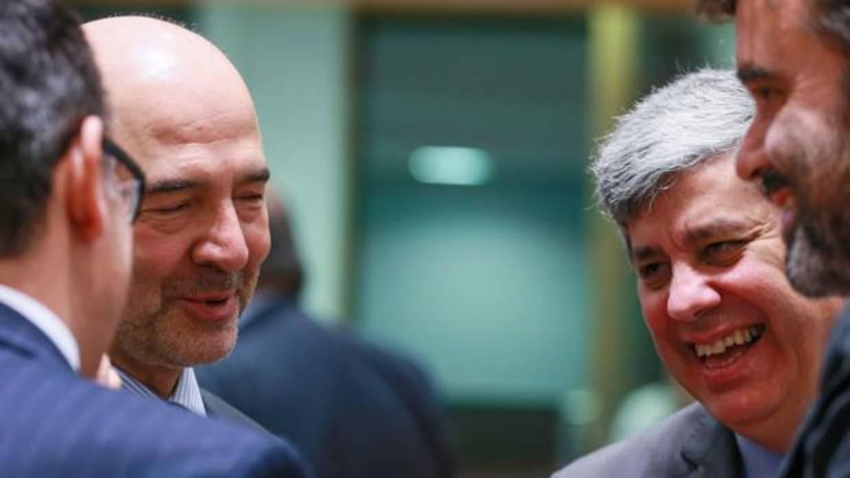 El comisario de Asuntos Económicos, Pierre Moscovici (izda) conversa con los titulares de Finanzas de España (izda) y de Portugal, Mario Centento quien también presidente el Eurogrupo