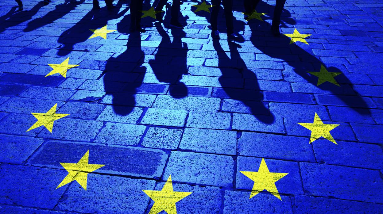 Las sombras de un grupo de personas sobre la bandera de la UE pintada en el suelo