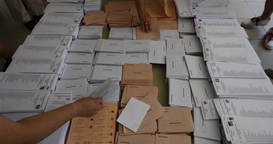 Papeletas de distintos partidos, dispuestas sobre la mesa de un colegio electoral