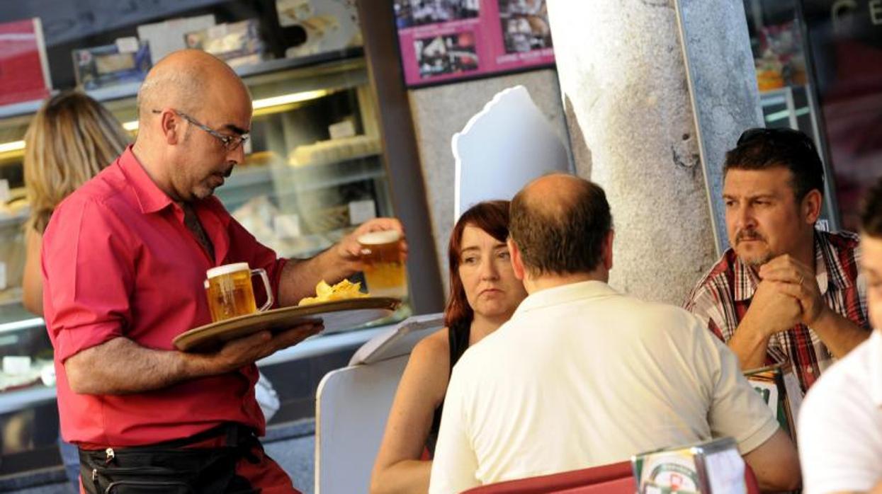 Un camarero atendiendo a unos clientes en la terraza de un bar