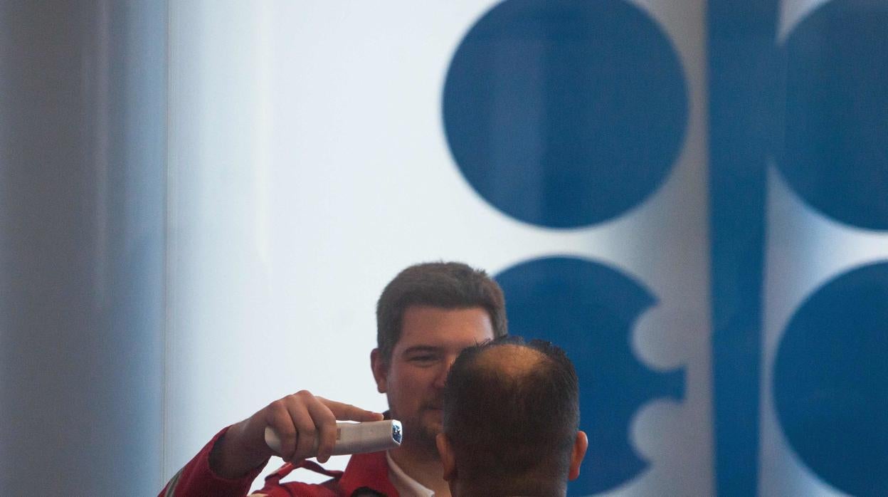 Personal de seguridad toma la temperatura a un asistente a la reunión de la OPEP en Viena