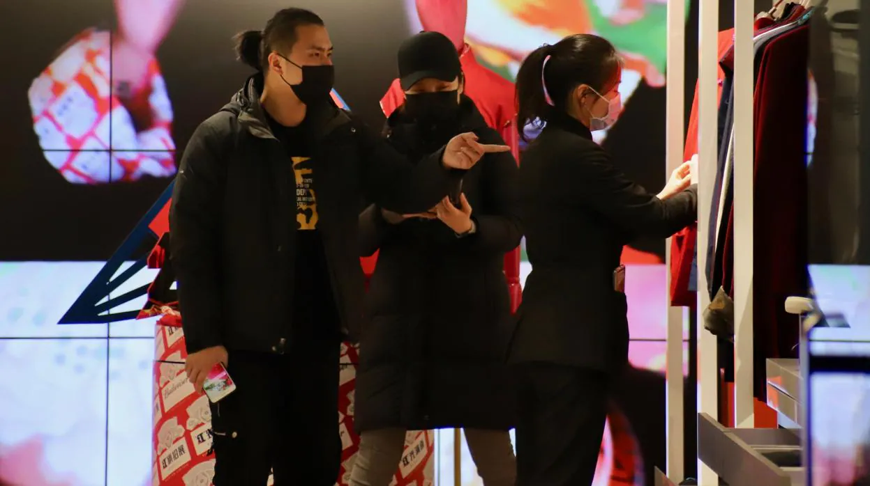 Dependientes y clientes se protegen con mascarillas en una tienda en Shanghái debido al coronavirus