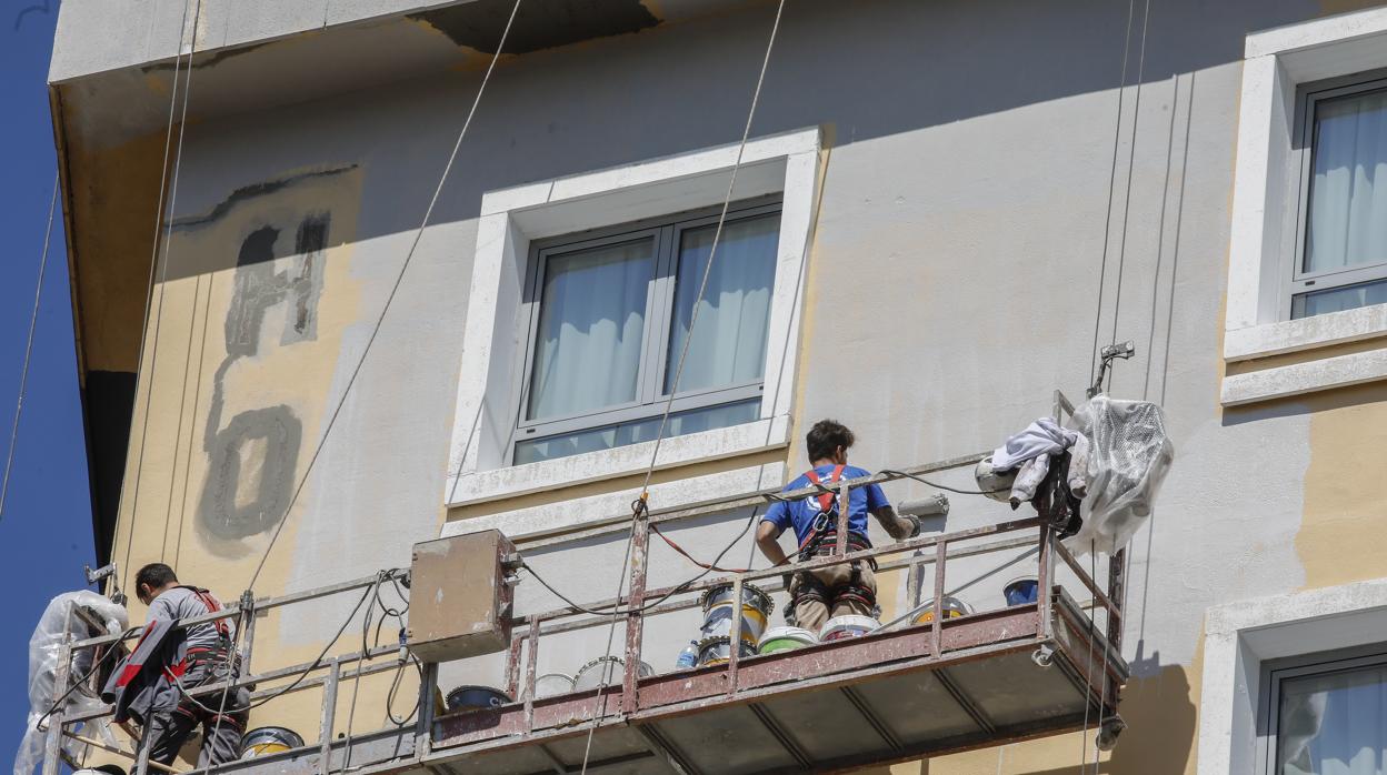 Dos personas realizan trabajos de mantenimineto de la fachada